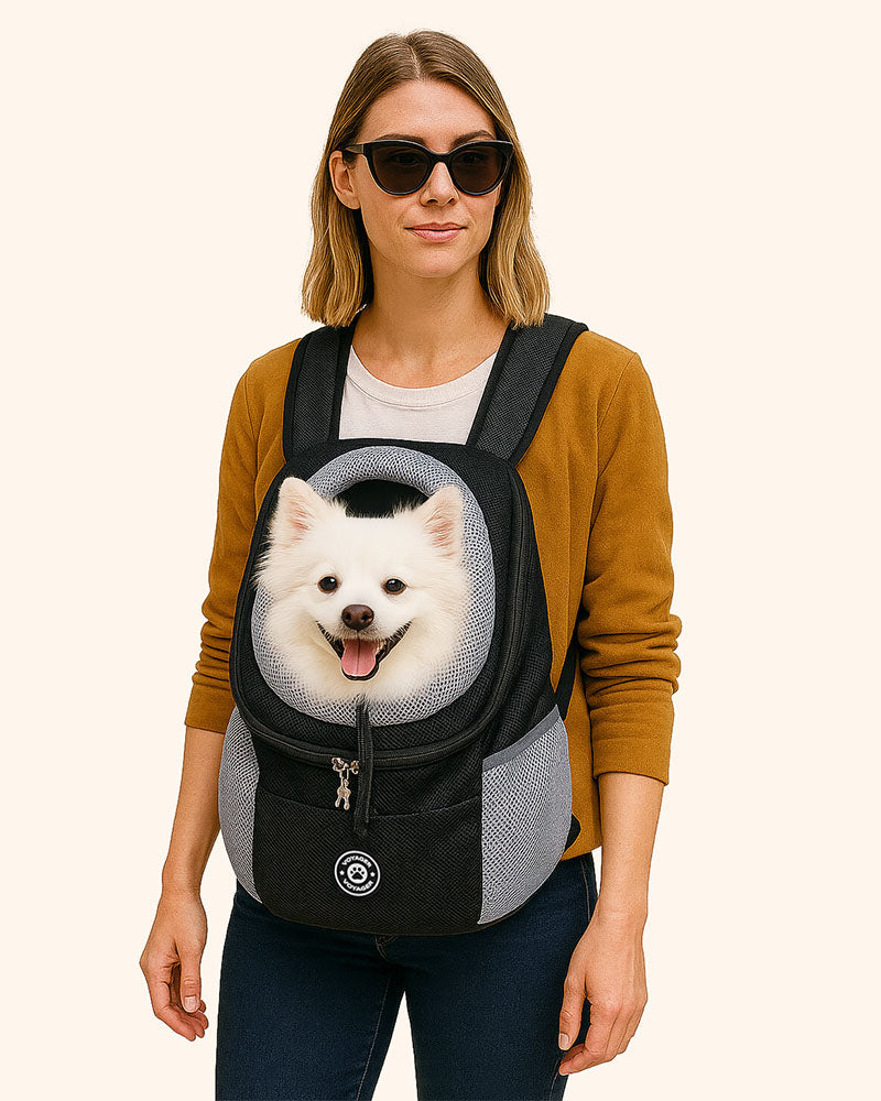Woman wearing a black/gray mesh pet carrier with a white dog inside 